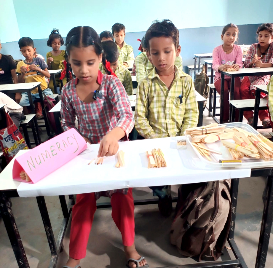 Primary school children in India practising numeracy with counting sticks at their desks